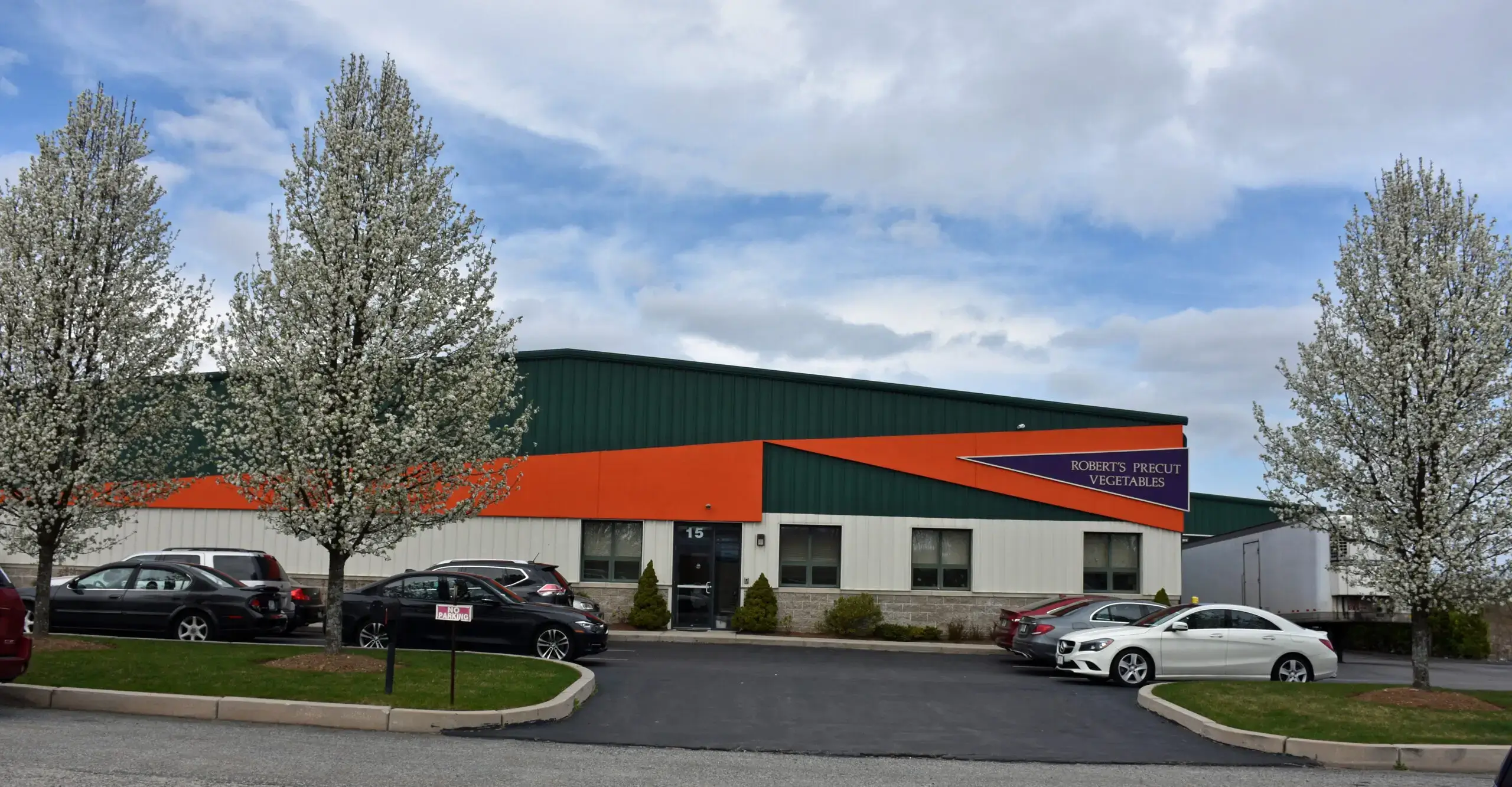 Industrial building with parking and trees.
